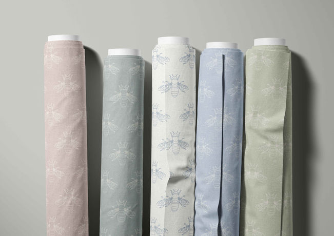 5 rolls of fabric with a bee design pattern in 5 different colour ways.