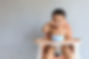 Happy infant Asian baby boy eating food by himself on baby high chair and making mess with