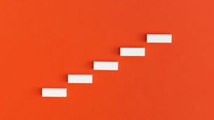 Minimalist white blocks arranged in ascending steps on a red background, representing structured brand growth and strategic progression.