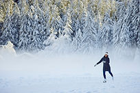 Eislaufen am Piburger See, Eisläuferin, Schnee, Bäume von Schnee bedeckt