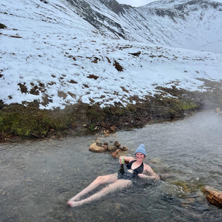 a girl soaking in the reykjadalur hot springs thermal river in Iceland