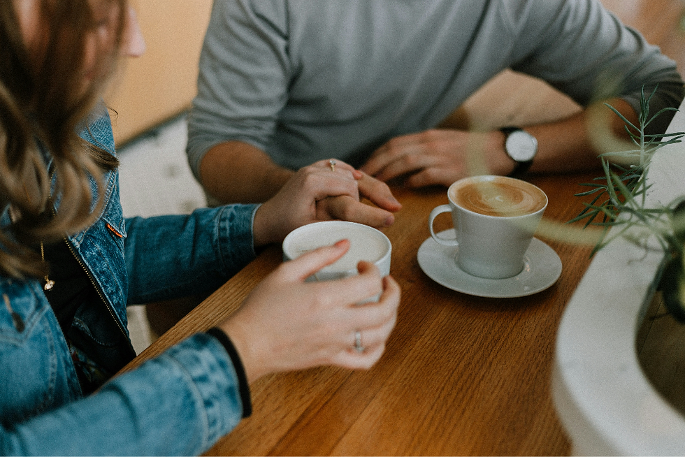 Couple holding hands across a café table with coffee cups, warm and intimate mood