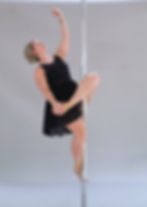 Eine blone Frau in tänzerischer Pose beim Poledance.