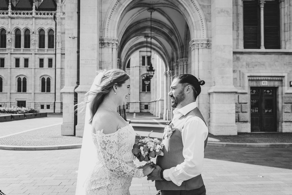 Bride and Groom facing each other in front of a historical landmark in budapest