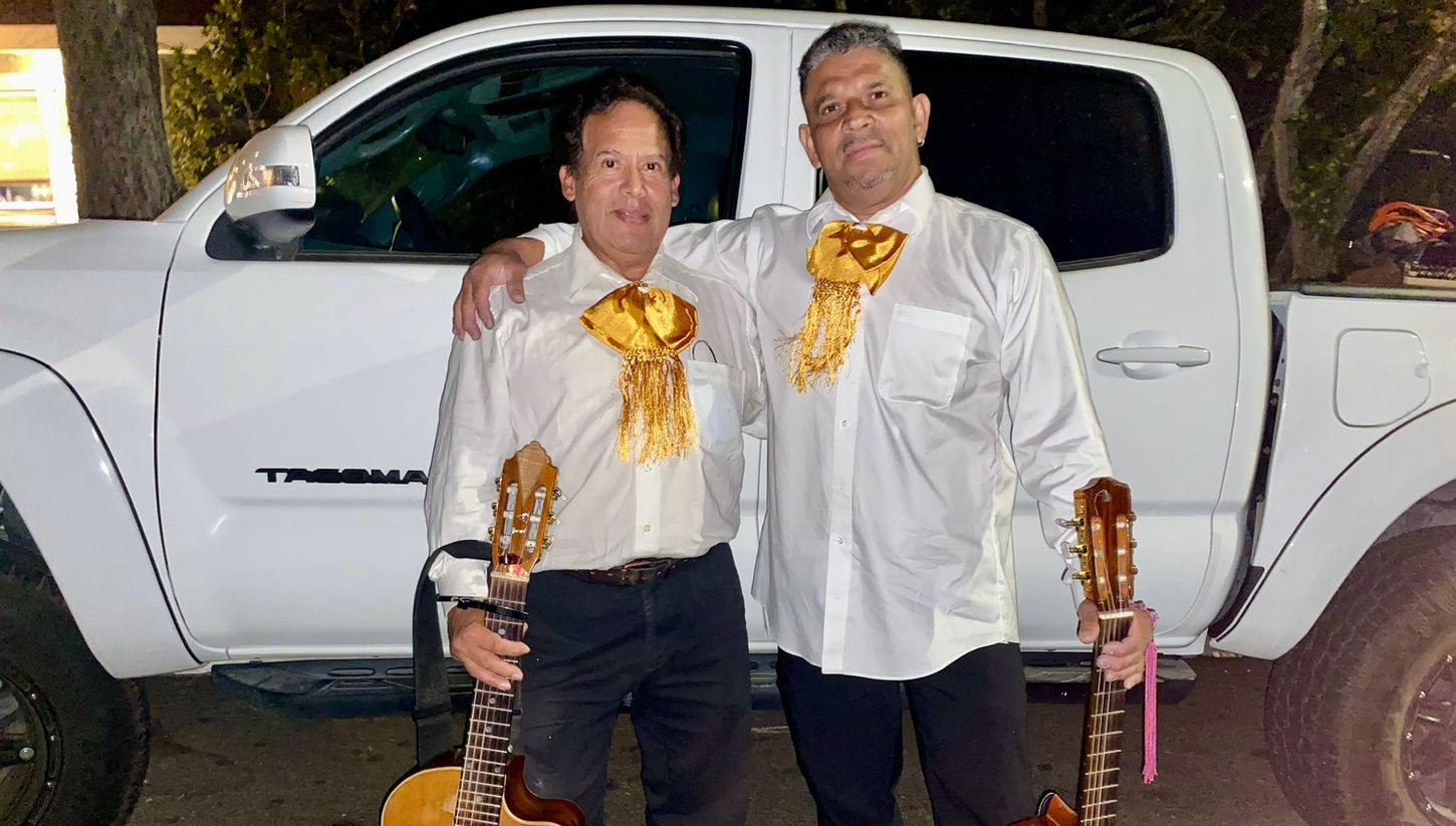 Members of Trio Mariachi Tepatitlan in mariachi uniforms holding guitars, showcasing their musical talent and traditional Mexican music style