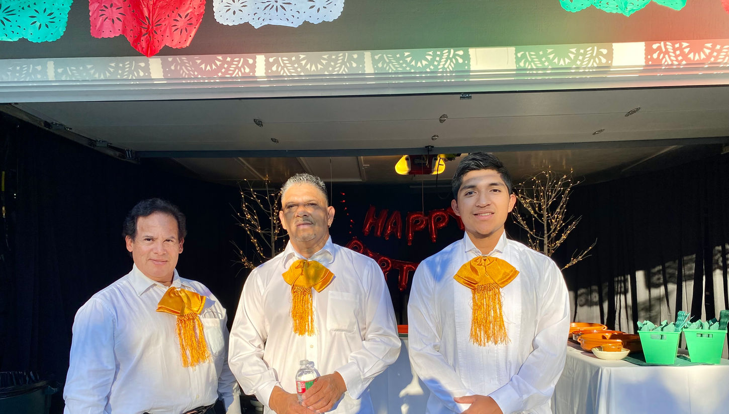 Trio Mariachi Tepatitlan performs at a summer house party in the Bay Area, near San Francisco and San Jose, dressed in vibrant mariachi attire, playing lively Mexican music and energizing the event with their skilled guitar performance.