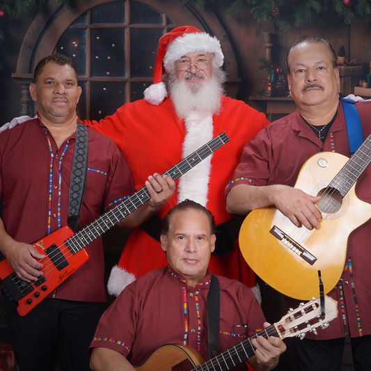 Trio Mariachi Tepatitlan posing with Santa Claus, holding guitars and wearing festive red uniforms.