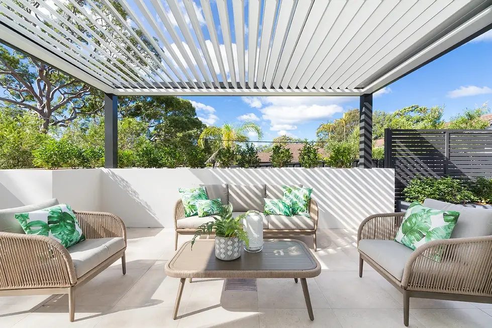 Outdoor patio with retractable roof, seating area, and plants.






