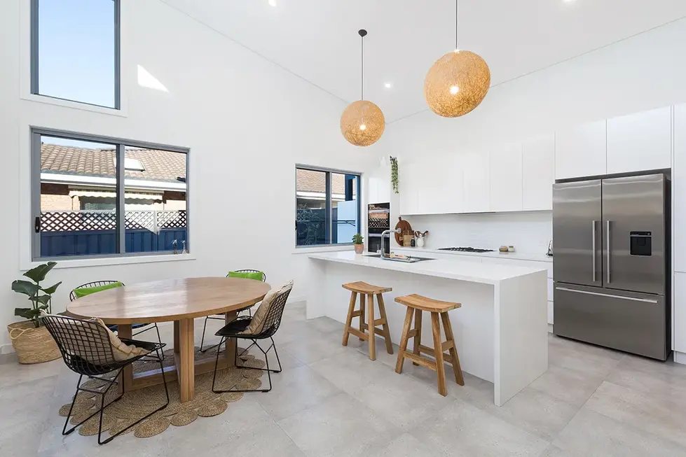 a kitchen with a table and stools and a stainless steel refrigerator