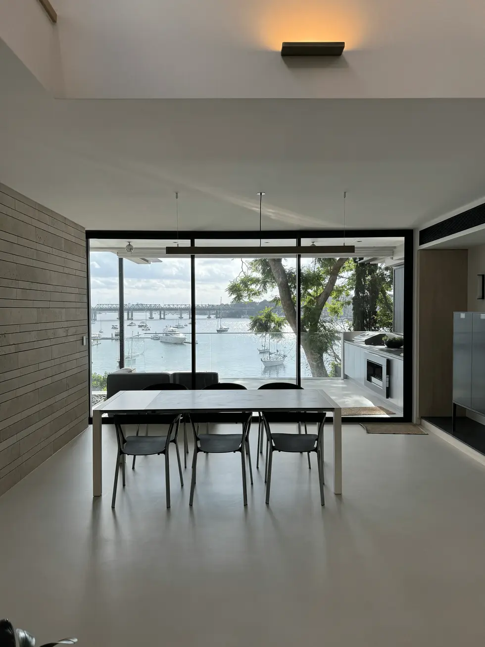 Modern dining room with large table and chairs overlooking waterfront.