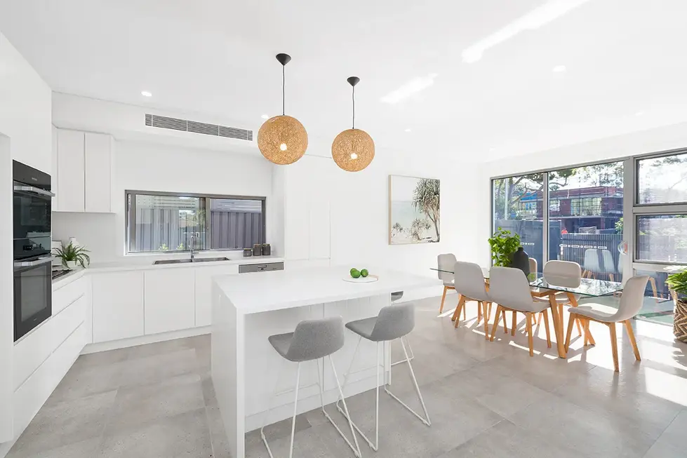 Modern kitchen with white cabinets, stainless steel appliances, kitchen island, and dining table.