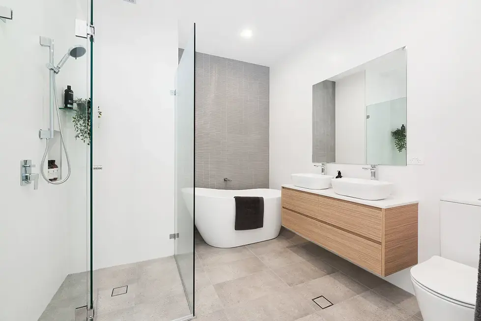 Modern bathroom with freestanding bathtub, dual sinks, and shower.