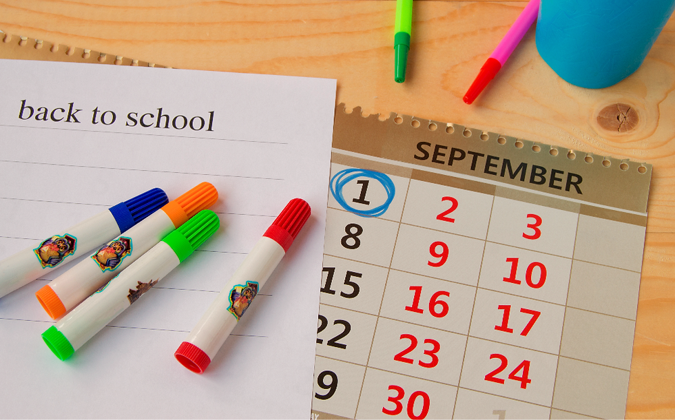 Markers and a "Back to School" sheet on wood table. September calendar with the 1st circled. Emphasizes school season start.