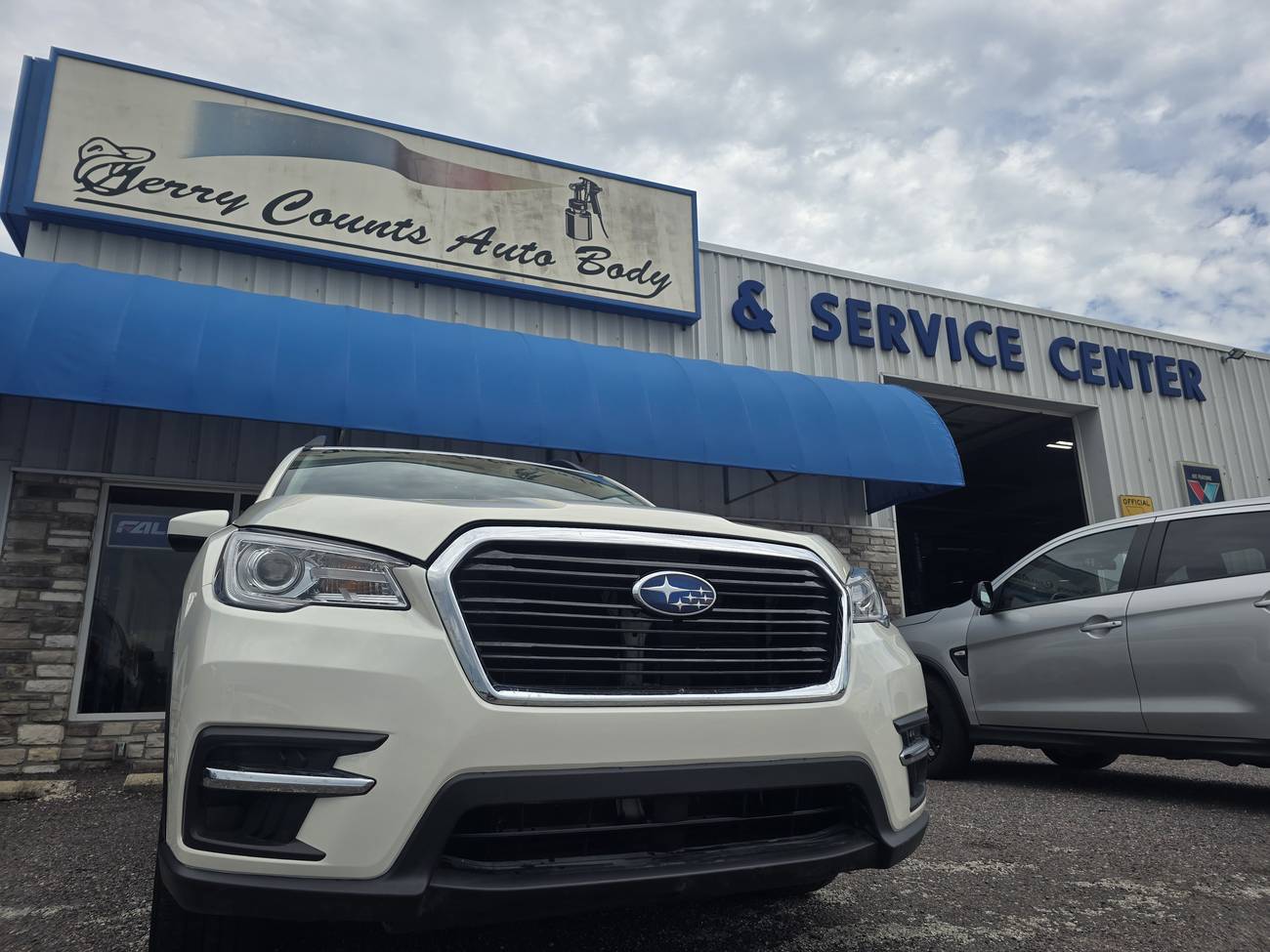 Same Subaru repaired, parked in front of the shop
