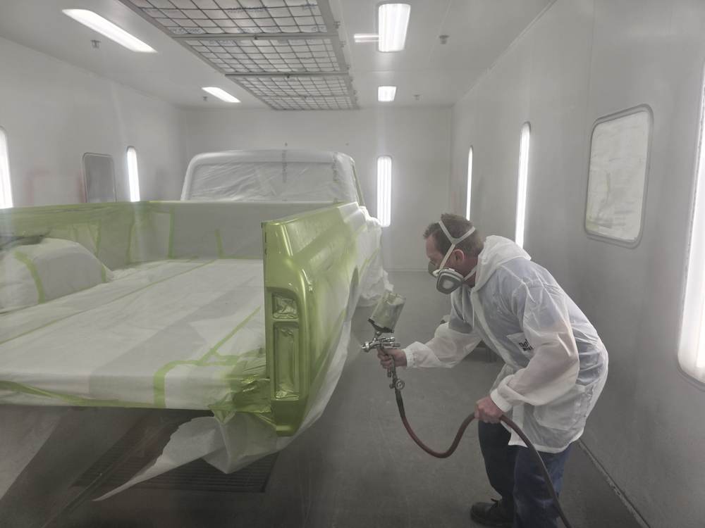 Painter spraying a truck bed in the booth