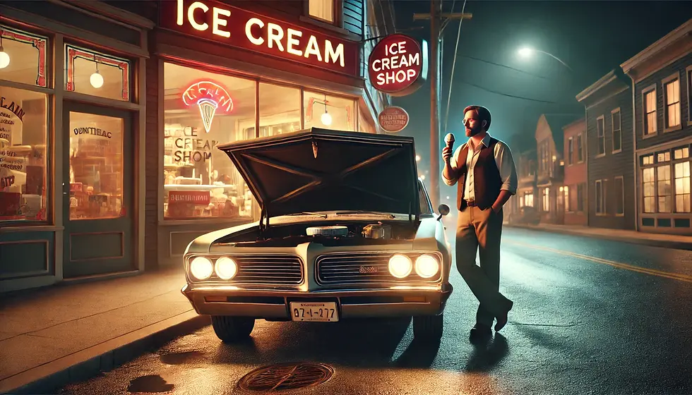 A man stands beside his car with the hood open, holding a an ice cream cone in front of a warmly lit ice cream shop at night.