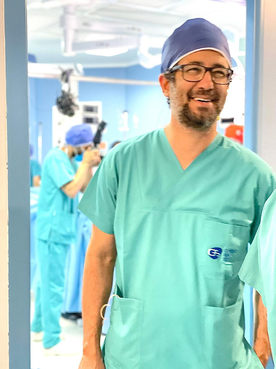 Prof. Dr. Suleyman Tas smiling in green surgical scrubs