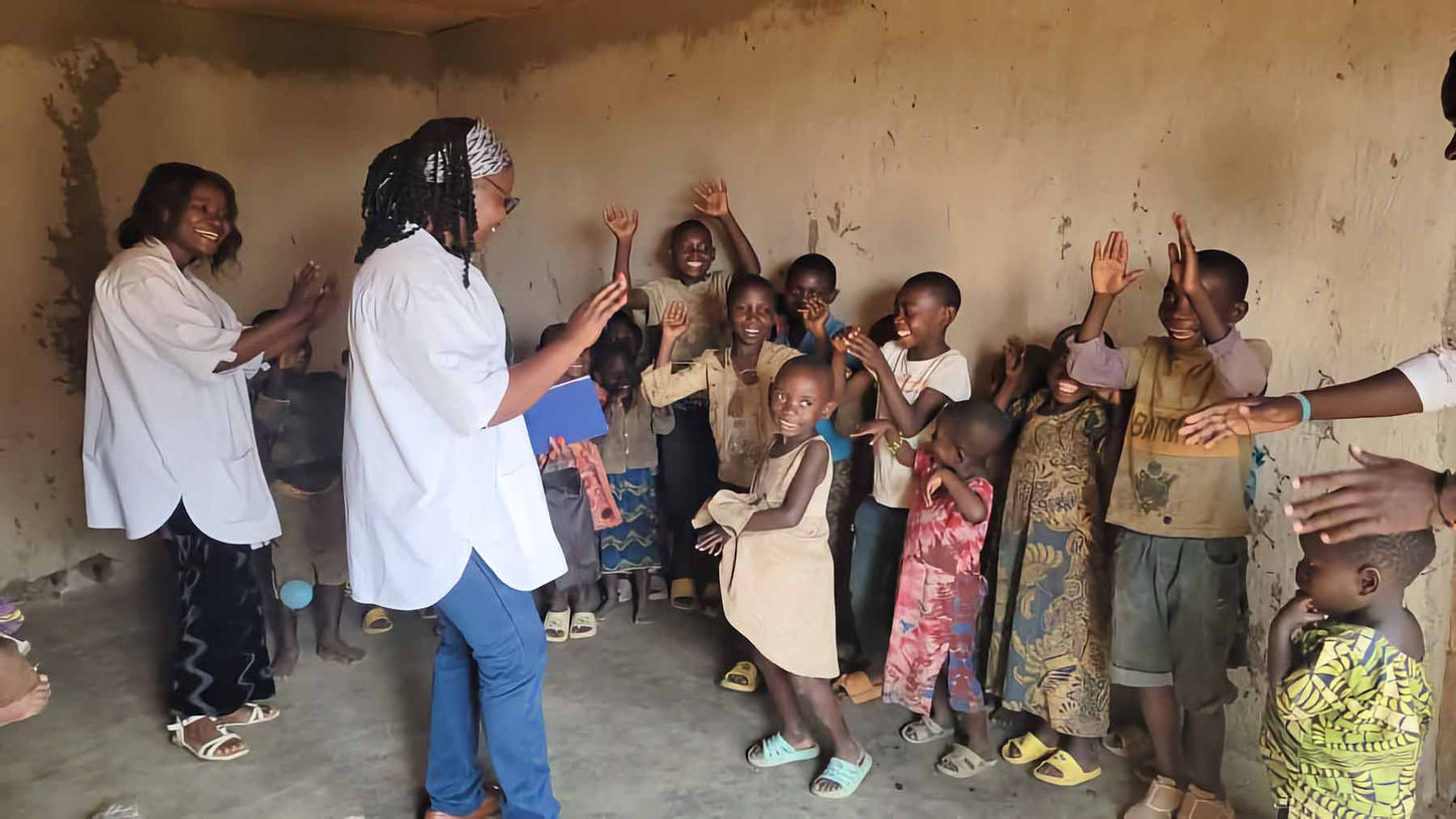 Session de sensibilisation sanitaire à Kisiza : deux femmes échangent avec des enfants pygmées joyeux, dans le cadre du projet santé porté par Dr Pamela.