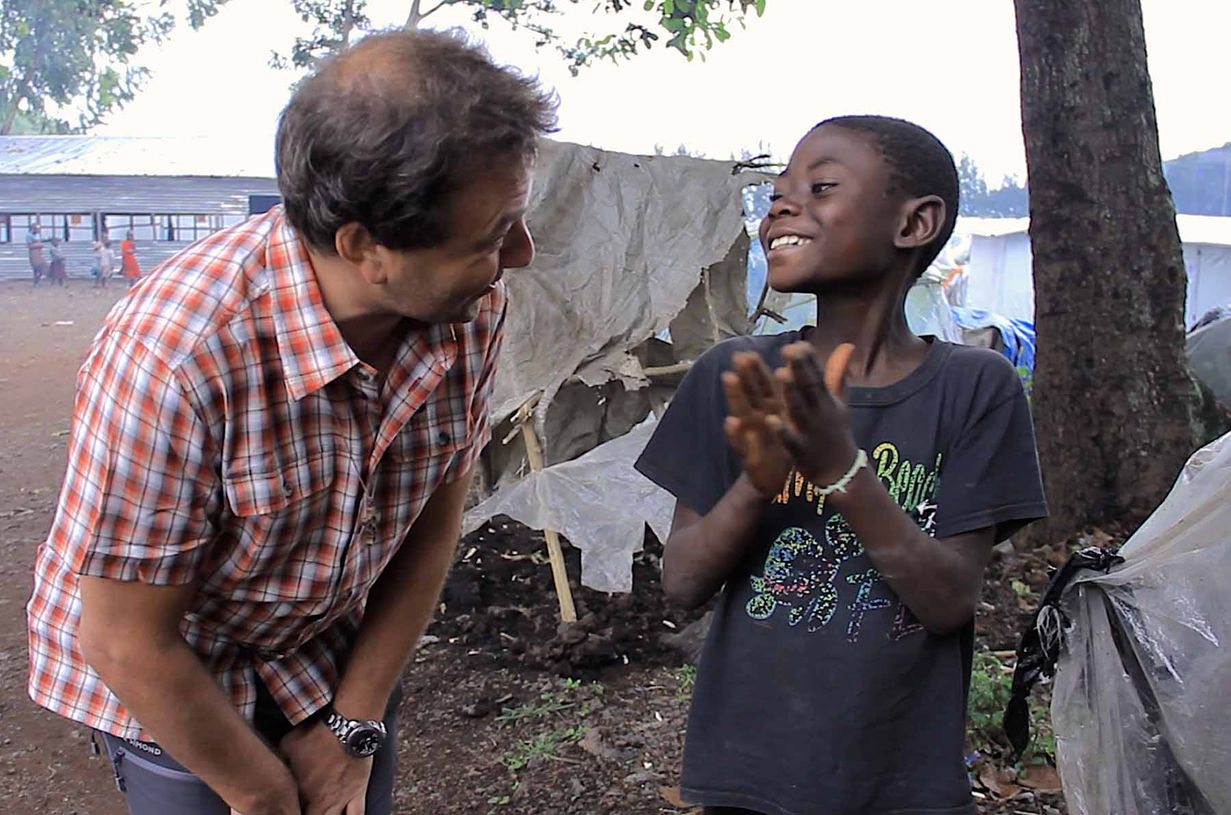 Chanoine José Mittaz en interaction bienveillante avec un enfant à Bukavu, image symbolique du lien direct avec les populations locales.