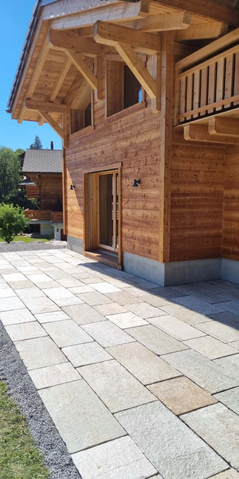 Terrasse dallée en pierre naturelle, s’intégrant parfaitement au cadre montagnard d’un chalet.