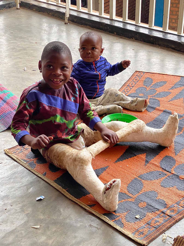 Deux enfants jouent à l’extérieur, l’un d’eux porte un plâtre, image symbolique du soutien médical apporté par les parrains et marraines.