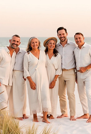 Family of five dressed in white standing together on a sandy beach at sunset