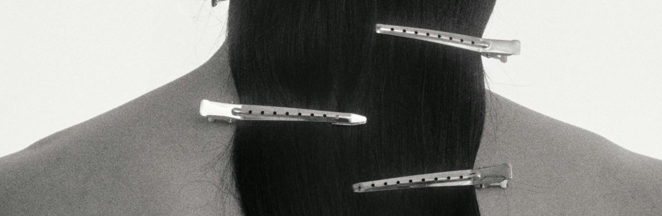 A woman with long hair, featuring numerous hair clips, poses in a stylish Korean hair salon.