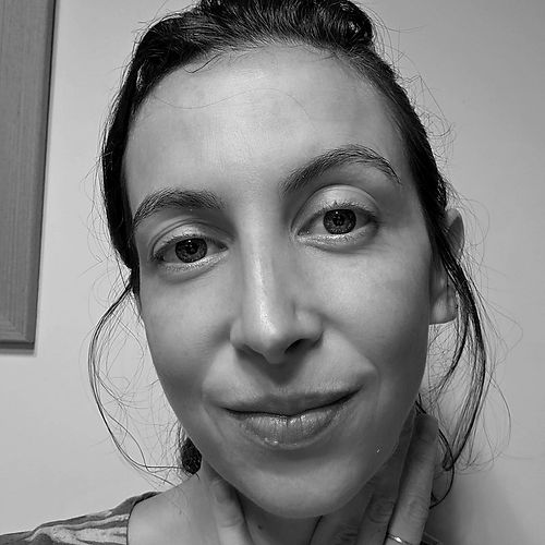 Rosto de Pilar, mulher branca, na faixa dos 38 anos, com cabelos presos e alguns fios soltos, sorriso discreto