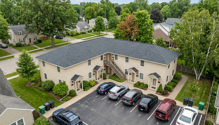 High-angle view of a multifamily rental building with parking spaces behind it.