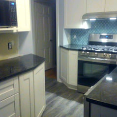kitchen with white cabinets, black counters and blue tile backsplash