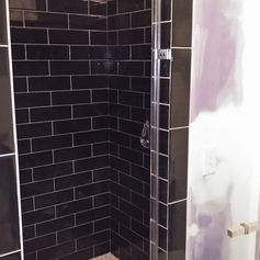 walk in shower with black subway tile