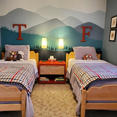 Mural painted in childs bedroom with stylized mountains and treelike using shades of green, blue and grey.