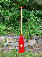 Wood paddle painted red with natural wood shaft and maple leaf design.