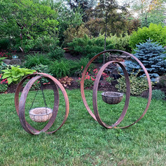 Garden art made with crossed wagon wheel rims and feature hanging basket frame with hypertufa planter