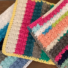 Cotton yarn remnants used to crochet textured dishcloths in striped pattern
