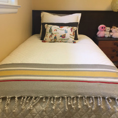 Chalk synthesis paint used to paint a red line on yellow, grey and white cotton throw blanket used at the bottom of a bed.