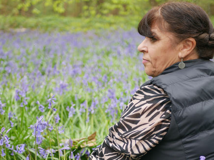 Woman sat in a field of bluebells with her back to the camera in pure euphoria