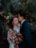 A groom kisses his bridges forehead standing amongst a flowering tree in the Brisbane Botanic Gardens