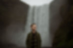 Young boy stands in front of waterfall during family photos by Iceland wedding photographer.