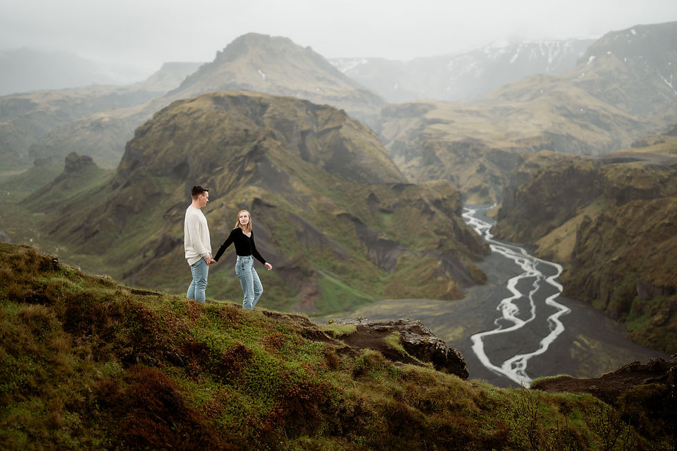 couple walking down grassy cliff edge in Thorsmork Iceland during engagement photo session.