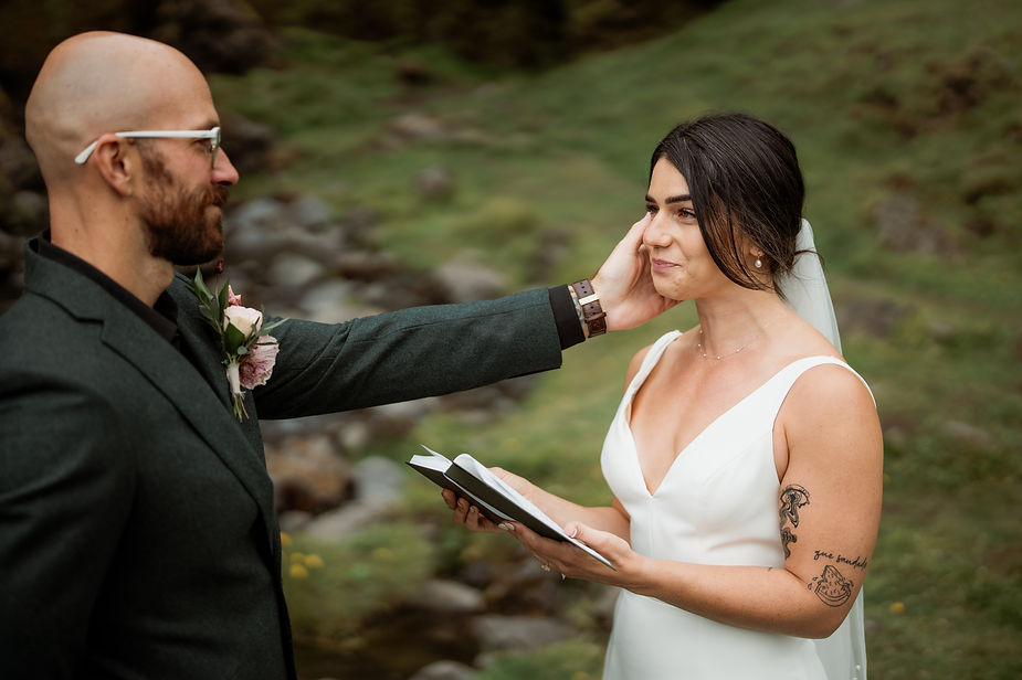 groom puts hands on brides face during wedding ceremony.