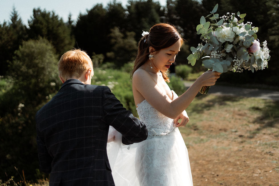 A person helps their partner with their dress during their iceland destination elopement photos.