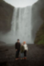 Family stands in front of waterfall during family photos with iceland elopement photographer.