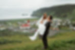 groom holds bride with town in the background during iceland intimate wedding photos.