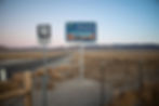 Nevada highway with signs reading "Welcome to Nevada" and "266 East," set in a desolate desert landscape at dusk, with mountains in view.