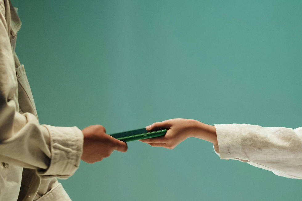 Two people exchange a green book against a teal background.