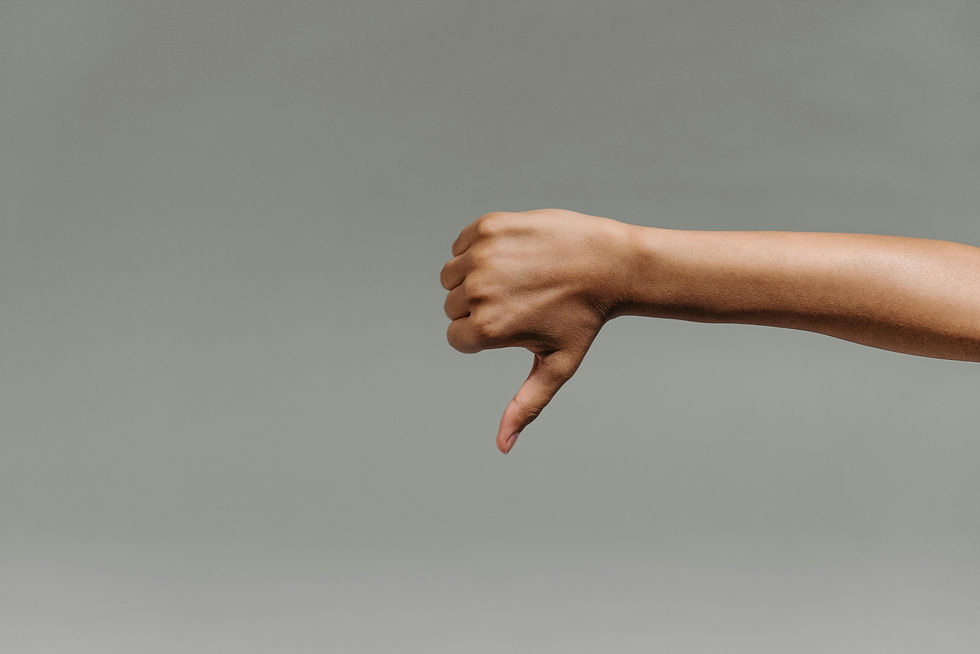 A hand giving a thumbs down against a grey background.