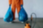 A man in an orange suit holding two full bin bags