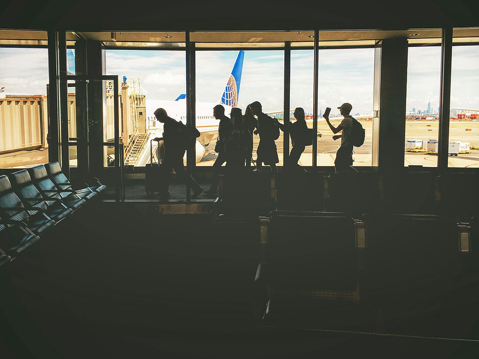 People lining up in the departure lounge of an airport with the plane in view out the window behind them