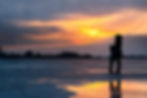 A mother and child stood on some ice with the sun setting behind them
